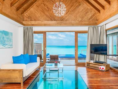 Wohnzimmer mit Holzmöbeln und Glasboden mit Blick auf das Meer und blauen Himmel.