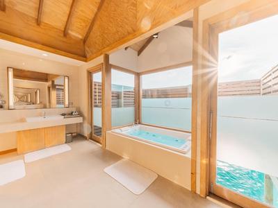 Helles Badezimmer mit Holzdecke, Badewanne vor Fenstern und Außentreppe zum Wasser.