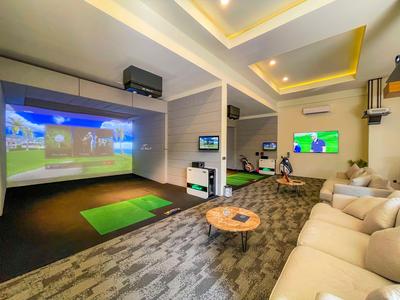 Modernes Indoor-Golf-Simulationszimmer mit Sofas, Teppichboden und großem Bildschirm.