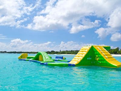 Aufblasbares Wasserhindernisparcours im klaren blauen Meer unter wolkigem Himmel.