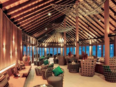 Modernes, gemütliches Hotelrestaurant mit Holzbalken und stilvollen Sitzmöbeln bei Dämmerung.