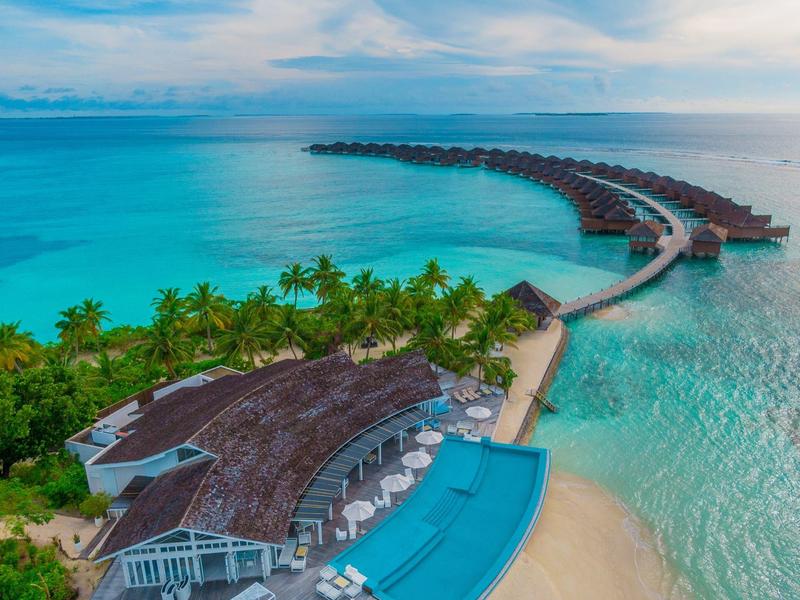 Luxuriöses Resort auf einer tropischen Insel mit Bungalows über dem Wasser und Infinity-Pool am Strand.