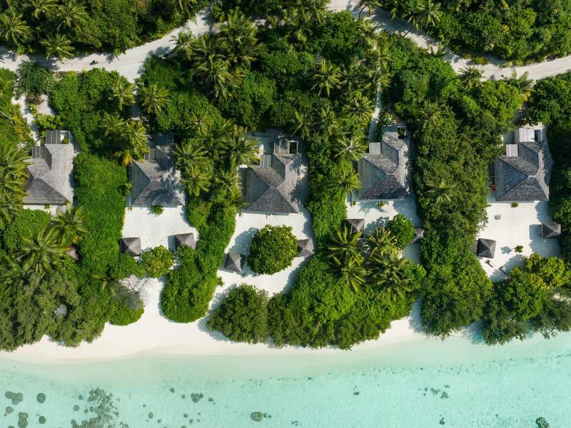 Luftaufnahme von fünf Villen am Strand mit weißem Sand und klarem türkisfarbenem Wasser