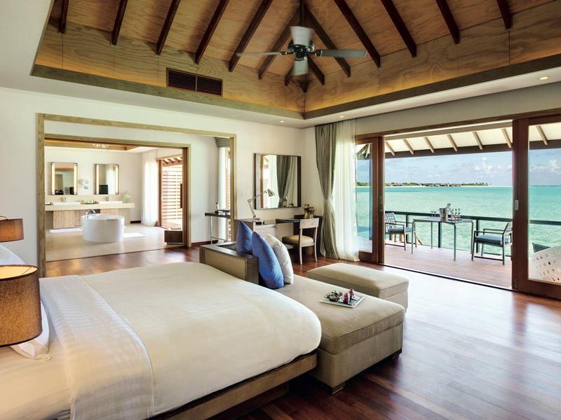 Helles Schlafzimmer mit Holzboden, großem Bett und Blick auf das Meer durch bodentiefe Fenster.