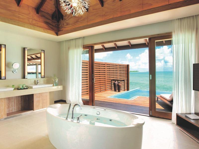 Modernes Badezimmer mit freistehender Badewanne und Meerblick durch große Glastüren.