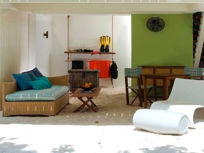 Moderne Terrasse mit weißem Boden, grünem Wandakzent, Holzmöbeln und gemütlicher Loungeecke.