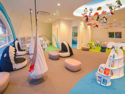 Buntes, geräumiges Kinderzimmer mit Sitzkissen, Hängesitz, Spielregal und bunten Dekorationen an der Decke.