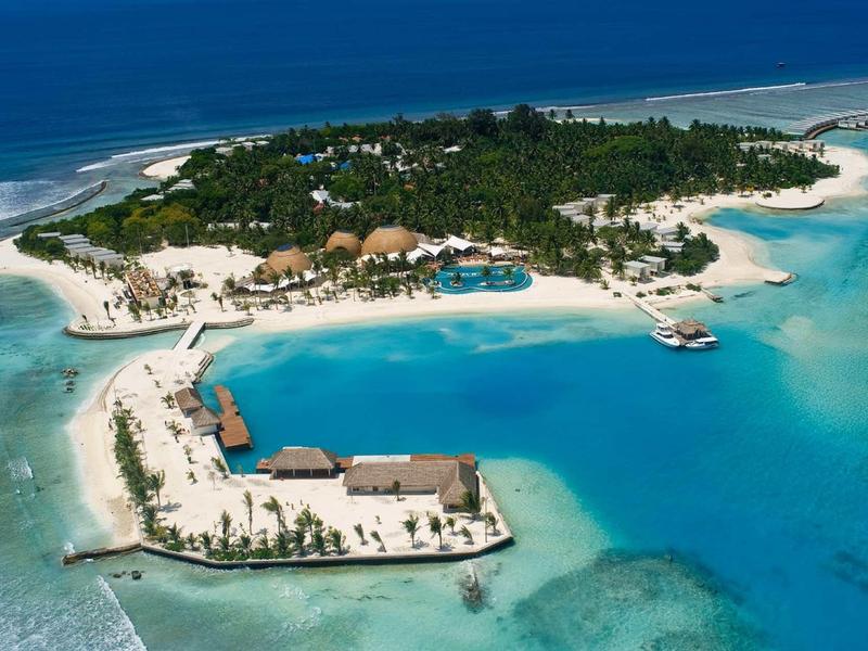 Tropische Insel mit weißem Sandstrand, türkisfarbenem Wasser und grüner Vegetation.