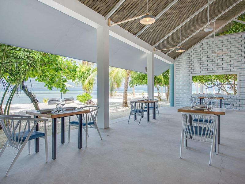 Großer Empfangsraum mit hölzernem Dach, modernen Kronleuchtern und Sitzgruppen aus Leder.