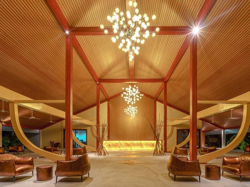 Großer Empfangsraum mit hölzernem Dach, modernen Kronleuchtern und Sitzgruppen aus Leder.