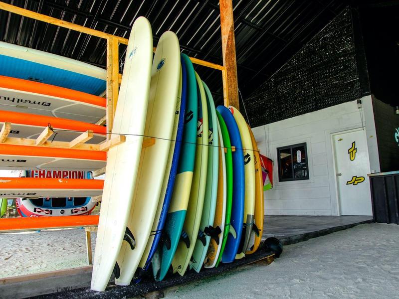 Mehrere farbige Surfbretter stehen in einem orangefarbenen Gestell in einer Halle.