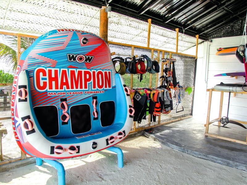 Bunte aufblasbare Wassersportplattform und bunte Schwimmwesten hängen in einer Halle.