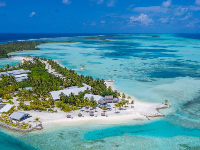 Tropische Insel mit weißen Sandstränden, grüner Vegetation und klarem türkisem Wasser.