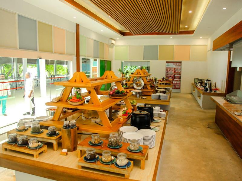 Buffetraum mit Holzregalen voller diverse Speisen, helle Räume und große Fenster mit Sicht nach draußen.