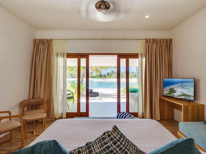 Schlafzimmer mit Doppelbett, Holzmöbeln, Vorhängen und Blick durch Glastüren auf Pool und Garten.