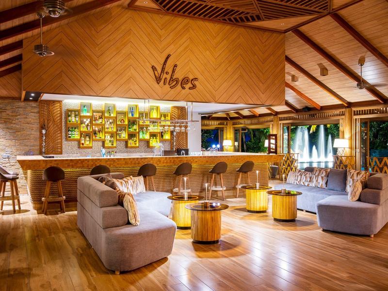 Innere einer modernen Bar mit Holzboden, gemütlichen Sitzgruppen und warmem Lichtkonzept.