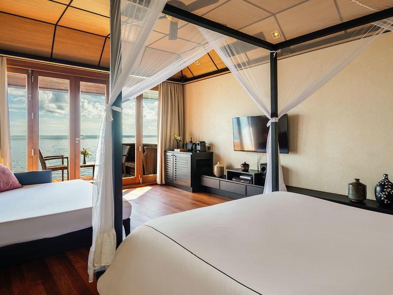 Geräumiges Schlafzimmer mit zwei großen Betten, Holzboden und großen Fenstern mit Blick nach außen.