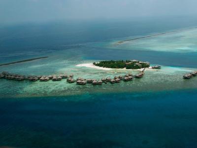 Blick auf türkisblaues Meer von Holzterrasse mit kleinem Pool und einfachen Holzmöbeln.
