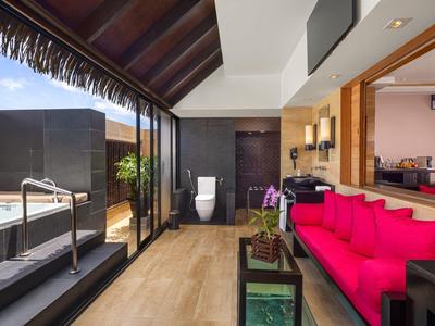 Moderne Lounge mit rotem Sofa, Glasschiebetür, Whirlpool und schwarzer Außenwand.