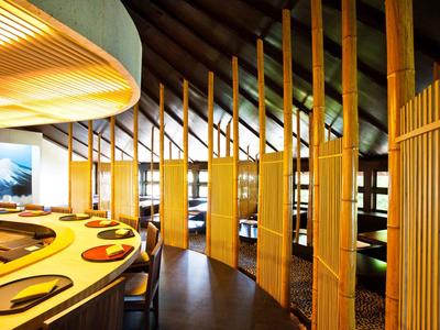 Modernes Restaurant mit gebogenen Holzteilen und eleganter, offener Raumgestaltung.