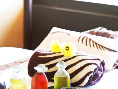 Ein Tablett mit Getränken und Seifen vor einem in Streifen gefalteten Handtuch auf einem Hotelbett.