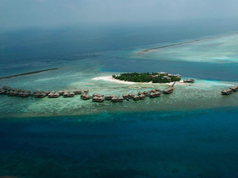 Blick auf türkisblaues Meer von Holzterrasse mit kleinem Pool und einfachen Holzmöbeln.