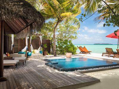 Espace piscine avec chaises longues et vue sur la mer dans un hôtel tropical.