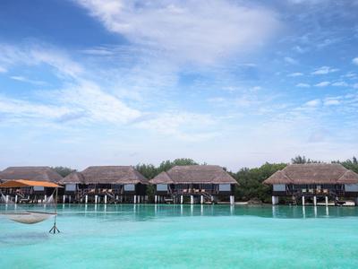 Alignement de bungalows sur pilotis sur une eau turquoise claire sous un ciel bleu.
