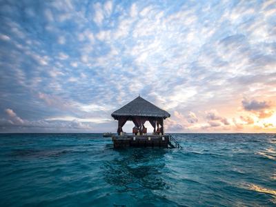 Pavillon en bois sur mer ouverte au coucher du soleil avec ciel nuageux