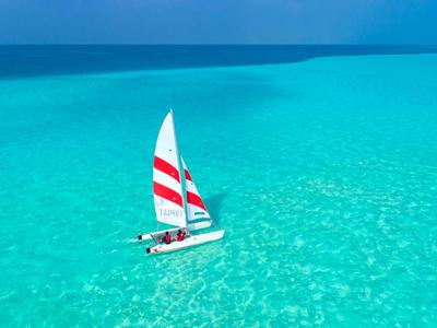 Voilier avec des voiles rouge et blanc sur une mer turquoise sous un ciel clair