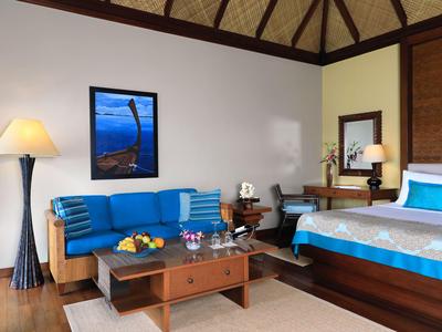 Une chambre d'hôtel confortable avec un canapé bleu, un lit en bois et des tons neutres.