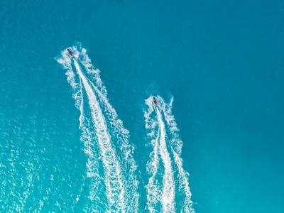 Deux bateaux naviguant sur une mer turquoise laissant des traînées blanches derrière eux.