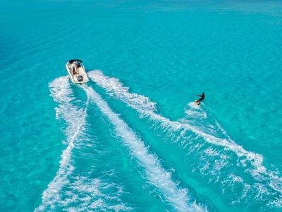 Personne tirée sur une planche derrière un bateau dans une eau turquoise claire.