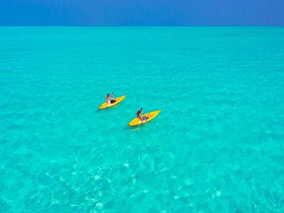 Deux personnes pagayant en kayaks jaunes sur une eau turquoise claire.