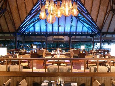 Restaurant chaleureux avec poutres en bois, éclairage chaud et nombreux sièges.