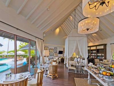 Helles Restaurant mit Holzdecke, gemütlichen Tischen und großer Glasfront mit Meerblick.