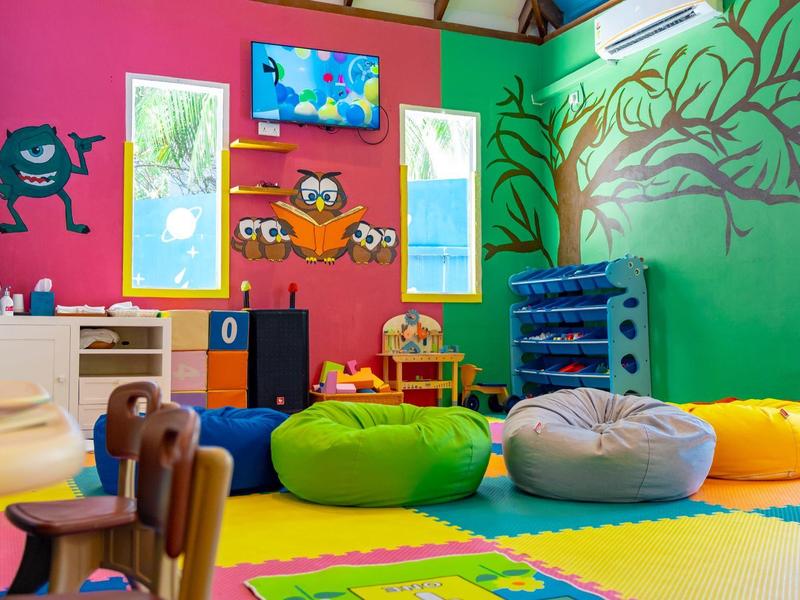 Bunt gestalteter Kinderspielraum mit Sitzsäcken, Spielfläche und Wanddekorationen.