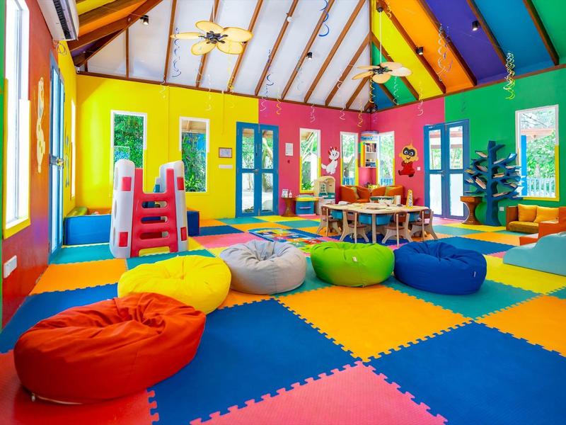 Bunter Spielraum mit Sitzsäcken, Spielzeug und bunten Wänden in einem Hotel oder Ferienort.