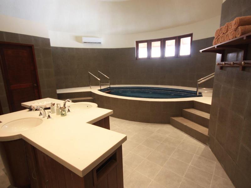 Innenraum mit rundem Whirlpool, Treppe, Waschbecken und modernen grauen Fliesen.