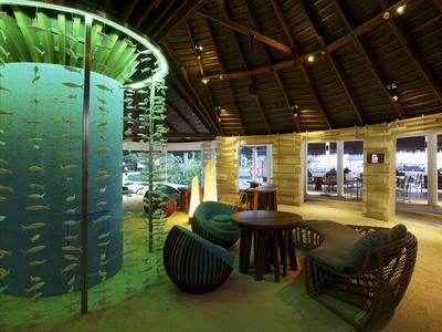 Gemütliche Hotel-Lounge mit Stühlen, Tischen und großen Fenstern unter einem Holzdach.