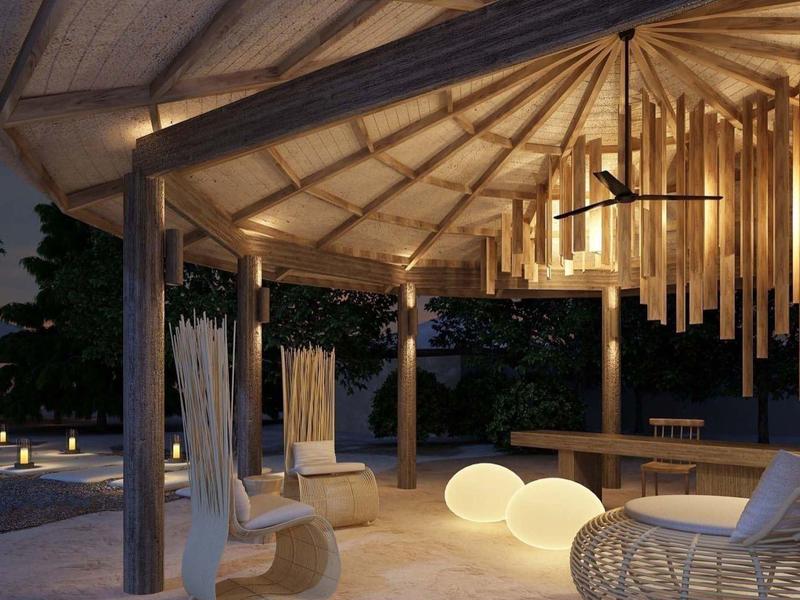 Beleuchtete Lounge mit modernem Mobiliar unter einem überdachten Bereich bei Abenddämmerung.