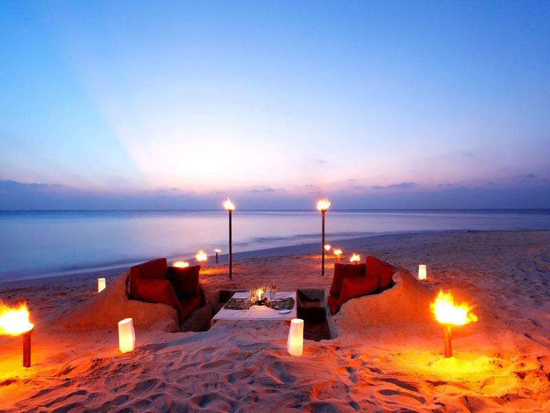 Gemütliche Sitzgruppe mit Feuerstellen am Strand bei Sonnenuntergang.