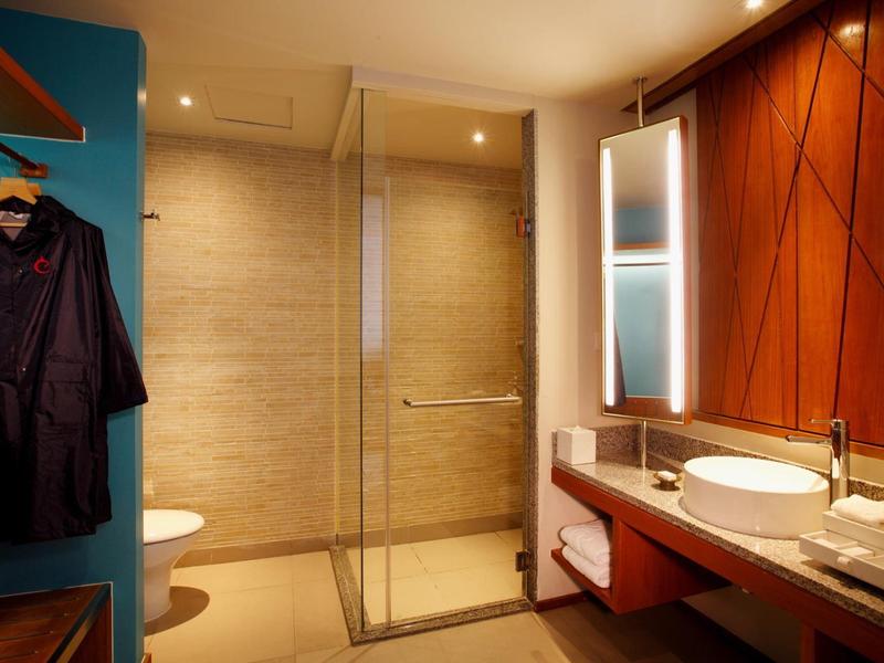 Modernes Hotelbad mit Glasduschkabine, Waschtisch und Holzverkleidung.