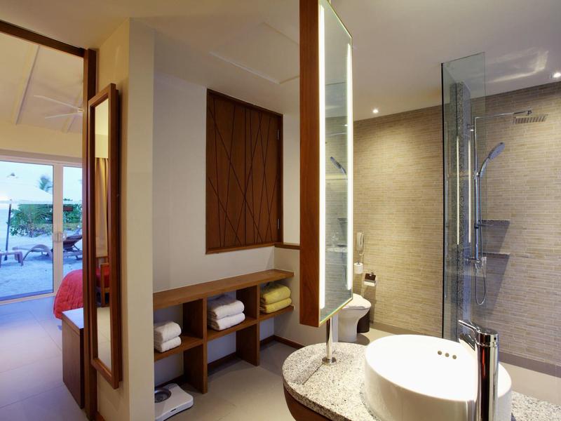 Moderner Hotelbadezimmerbereich mit Waschtisch, Spiegel und angrenzendem Zimmer mit Balkon