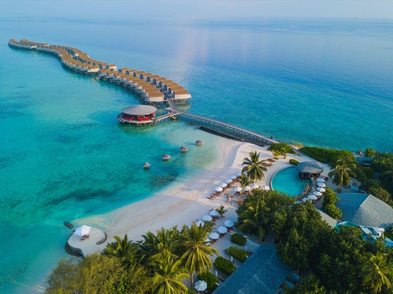 Luxuriöses Resort mit Überwasserbungalows, Sandstrand und Pool an kristallklarem Meer.