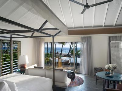 Modernes Hotelzimmer mit gemütlichem Sitzbereich und Blick auf Terrasse und Meer.