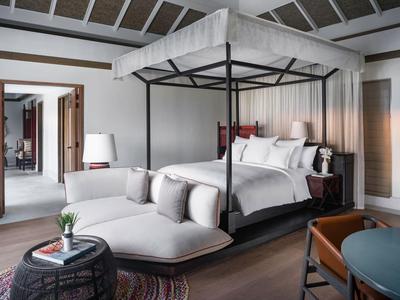 Modernes Hotelzimmer mit Himmelbett, Sitzbereich und großen Fenstern unter einem Glasdach.