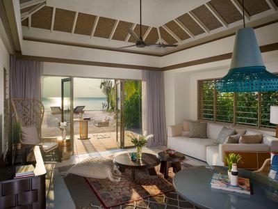 Helles Wohnzimmer mit modernem Design, Sofas, Teppich und Blick auf Terrasse mit Meer.