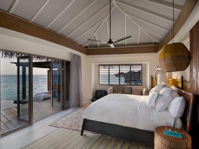 Luxuriöses Hotelzimmer mit großem Bett, Meerblick und Terrasse mit Sitzbereich.