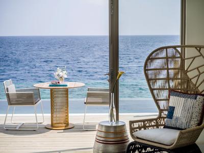 Moderner Balkon mit runder Tisch, Stühlen und Blick auf das offene Meer bei klarem Himmel.